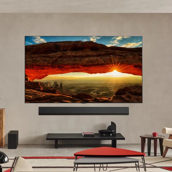 An LG TV and soundbar in a stylish living room setting. Screen shows a vivid image of a canyon as the sun sets beyond it. 