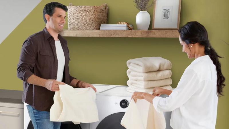 A couple folds laundry as they remove from dryer. 