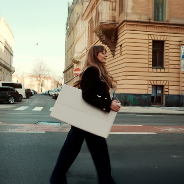 A woman carries a StanbyME portable touchscreen across the street with her over-the-shoulder case.