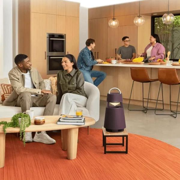 A group of friends converses in a stylish home. In the background we see an LG portable speaker as well as a double wall oven. 