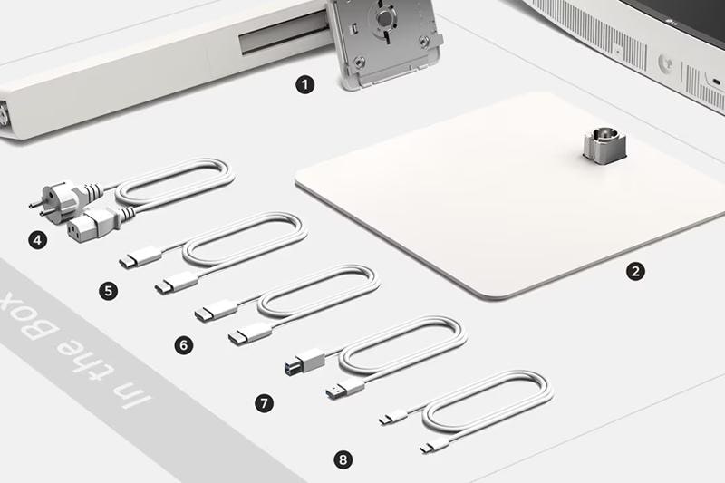 The image shows the contents of a box laid out systematically, each item marked with a number. At the top left corner, a long, rectangular white bar is labeled as item 1, next to a metallic mounting bracket. Adjacent to this, item 2 is a large, flat, square base plate with a metallic connector protruding from its surface. Below these, item 4 features two power cables with European plugs. Continuing in a row, items 5, 6, 7, and 8 are various cables with USB and USB-C connectors, each similar in design but differing slightly in connector type. The surface is white with light grey elements indicating where these items are placed.