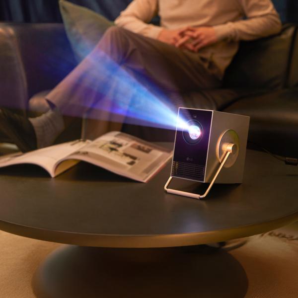 CineBeam Q projector projects as a person looks on.