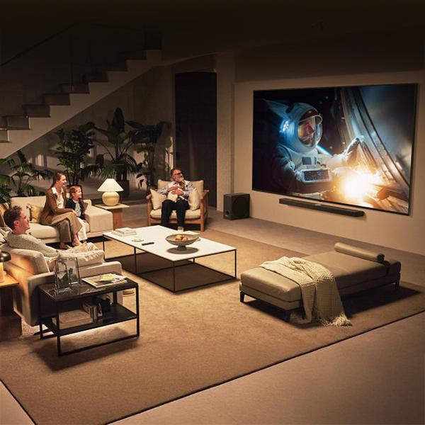 The LG 100 Inch Class QNED evo AI TV mounted on the wall of a modern living room with a family watching an astronaut on the screen.