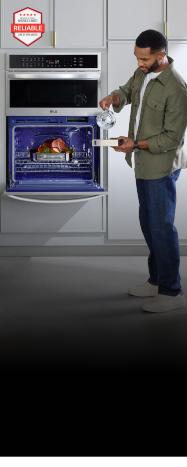 A mother slicing oranges for her daughter at the kitchen island while the father cooks a ham in their LG wall oven - mobile