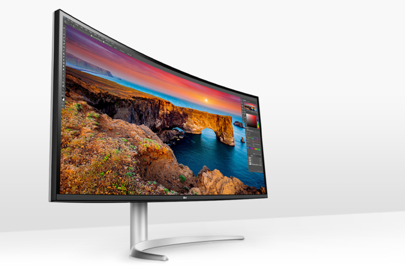 Curved computer monitor displaying a vivid landscape with editing software visible.