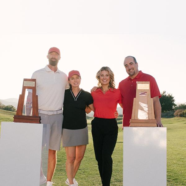 2 coaches pose with their partners as they stand behind their awards.