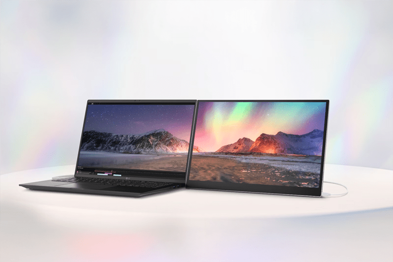 Two open laptops on a light surface, displaying colorful mountain landscapes.