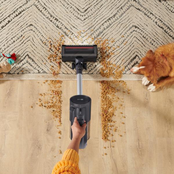 The LG CordZero™ Q3 Cordless Stick Vacuum Removable Cyclone with Crevice tool being used on a hardwood floor and carpet to pick up spilled dog food.