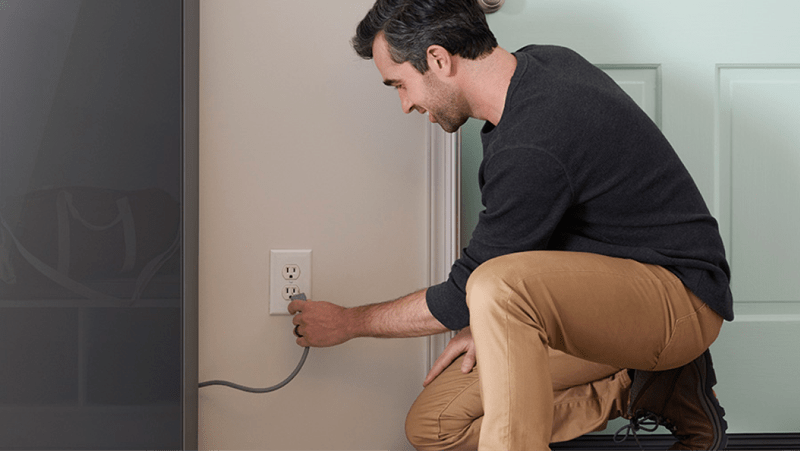 A man plugs an LG Styler® Steam Closet into an electrical outlet.