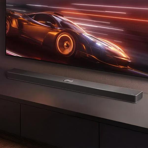 The LG S95AR Soundbar sits on top of console with a TV screen showing a car behind it.