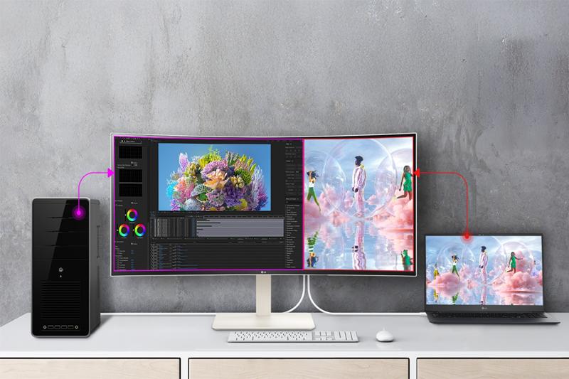 A desktop computer, a curved monitor, and a laptop are interconnected on a desk with digital art displayed.