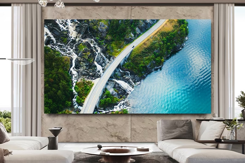 Modern living room with large TV showing an aerial coastal scene with road, cliffs, and ocean.