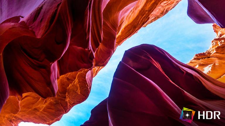 View of Antelope Canyon with colorful rock formations and a blue sky above.