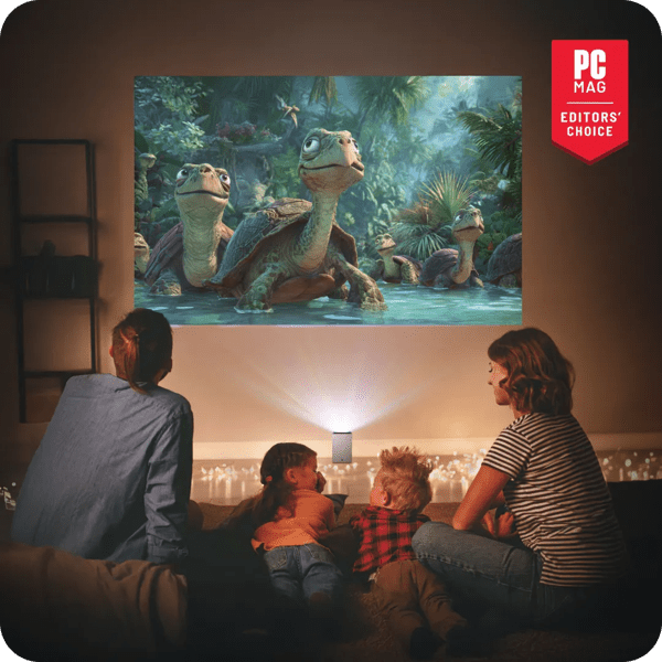 A family sitting and watching an animated movie with cartoon tortoises projected on a wall by an LG CineBeam S projector in a living room with ambient string lights on the floor. A red badge reading “PC Mag Editors’ Choice” is in the top right corner.