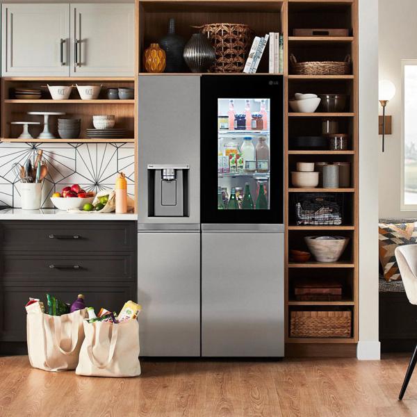 The LG Side-By-Side InstaView Refrigerator in a modern kitchen with rich wood accents. Grocery bags sit on the floor next to it.