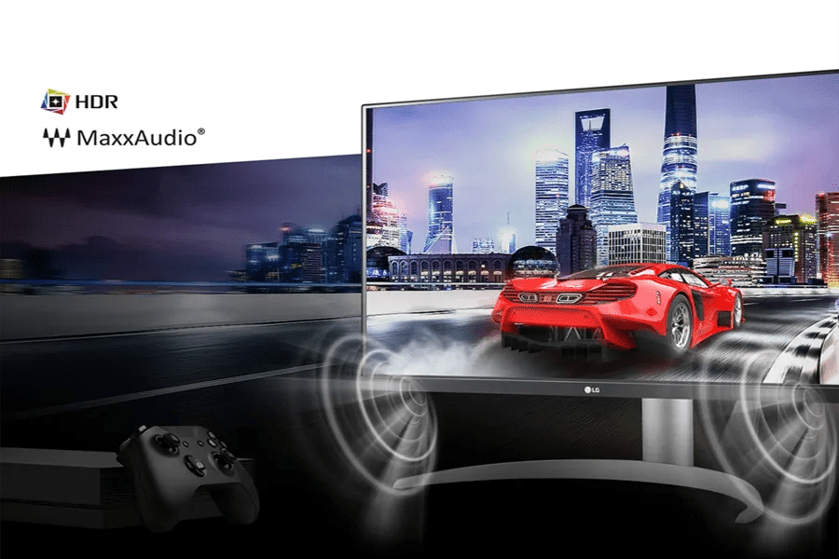 A gaming setup with an LG monitor showing a red sports car driving in a brightly lit cityscape, with HDR and MaxxAudio logos.