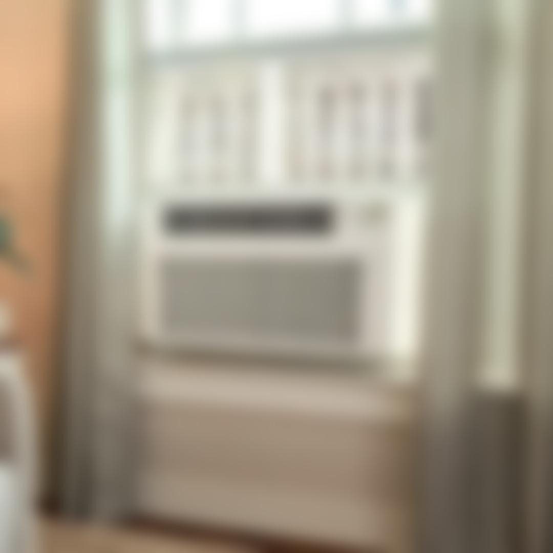 Labor Day Savings -- LG window air conditioner installed in a window with curtains, digital display panel, and vented front grille