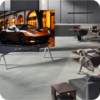 Man and dog in a high-rise living room apartment look at a bright sports car on an LG TV atop a movable stand.