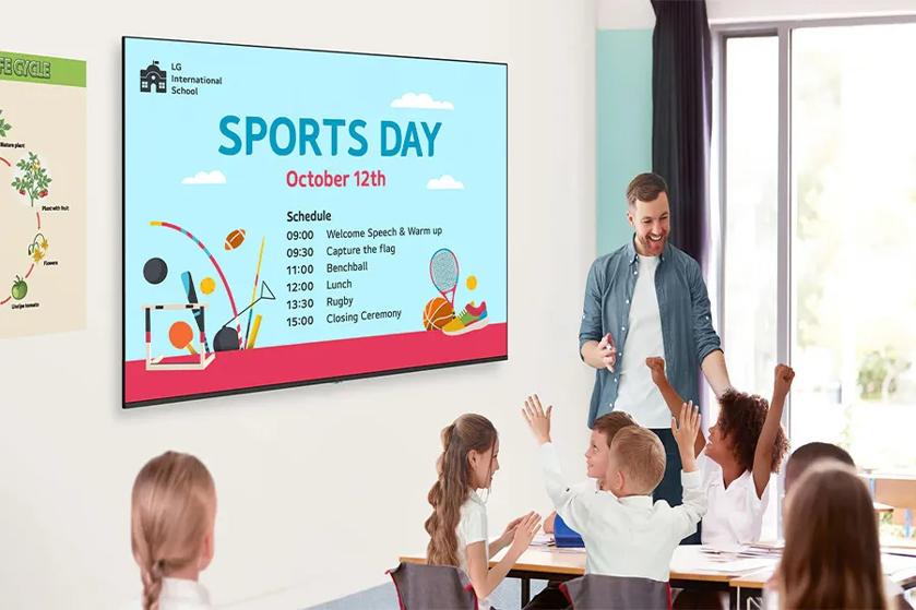 Classroom with students and teacher in front of a screen displaying Sports Day information.