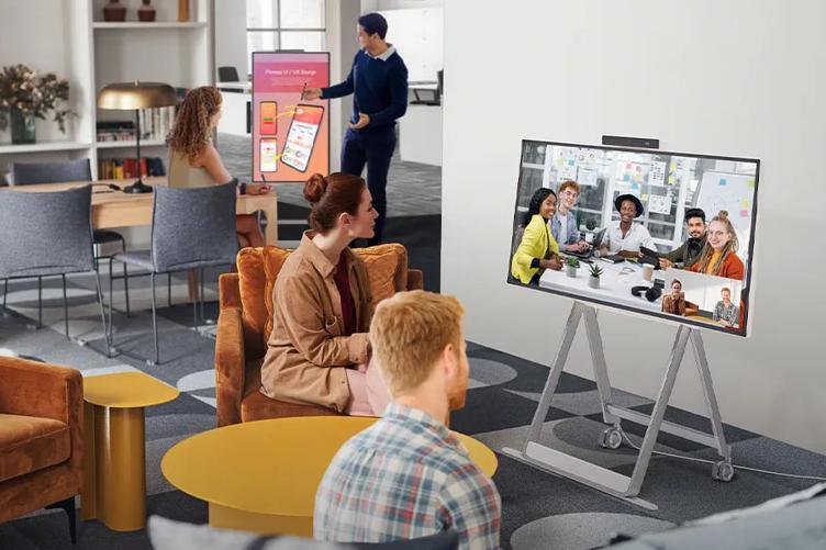 Two people sit in front of One:Quick Flex, having a video call with another office.