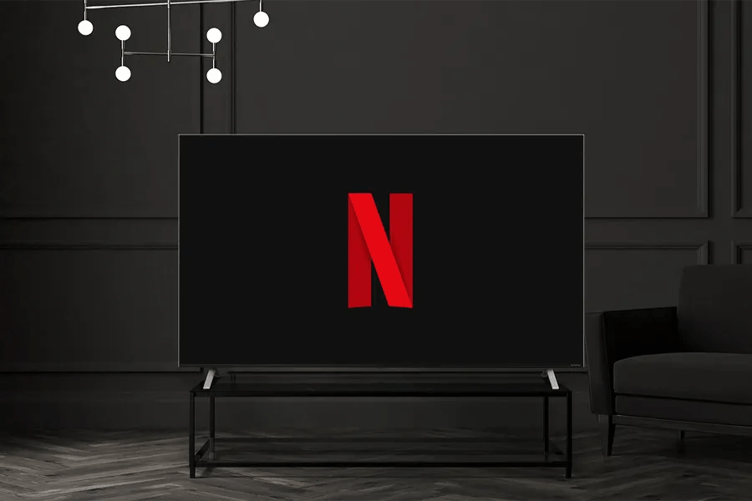 A chic hotel room with the lights turned down low. An LG Pro:Centric Hotel TV sits on a modern TV table, with the Netflix logo on its screen. 
