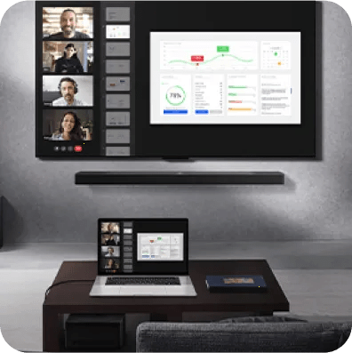Home office setup with a wall-mounted LG TV mirroring the screen on a laptop showing a video call and charts, and with no visible wires.