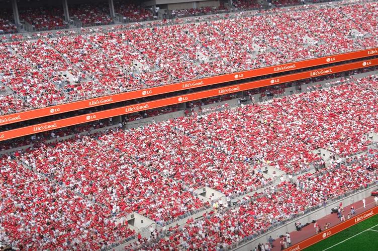 A crowded stadium with spectators wearing red and white, featuring "LG - Life's Good." banners.