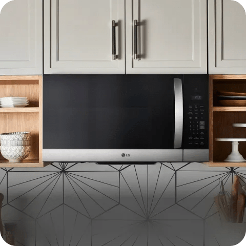 Over-the-range LG microwave with a wide viewing window and stainless finish, shown mounted under wood cabinets with the control panel at right.