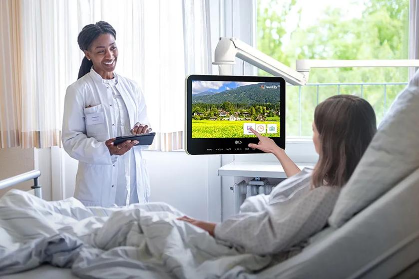 A doctor and patient in a hospital room interacting with an LG touch screen hospital TV.
