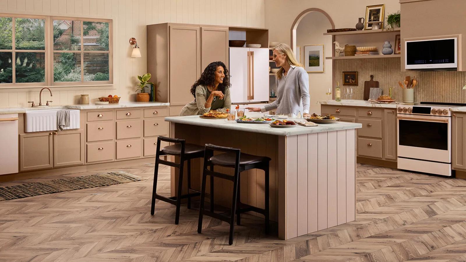 Two women in a modern kitchen setting, showcasing various LG Signature Collections and appliances.