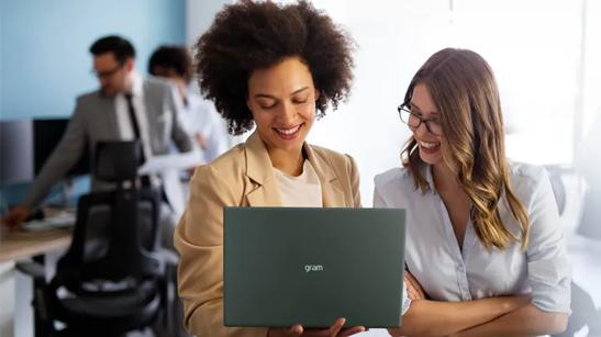 Two women in an office looking at an LG gram laptop