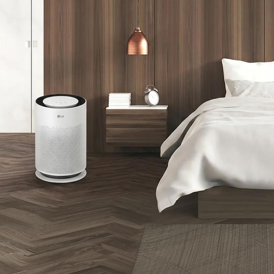 Modern bedroom featuring an LG PuriCare air purifier beside the bed in a clean, minimalist space.
