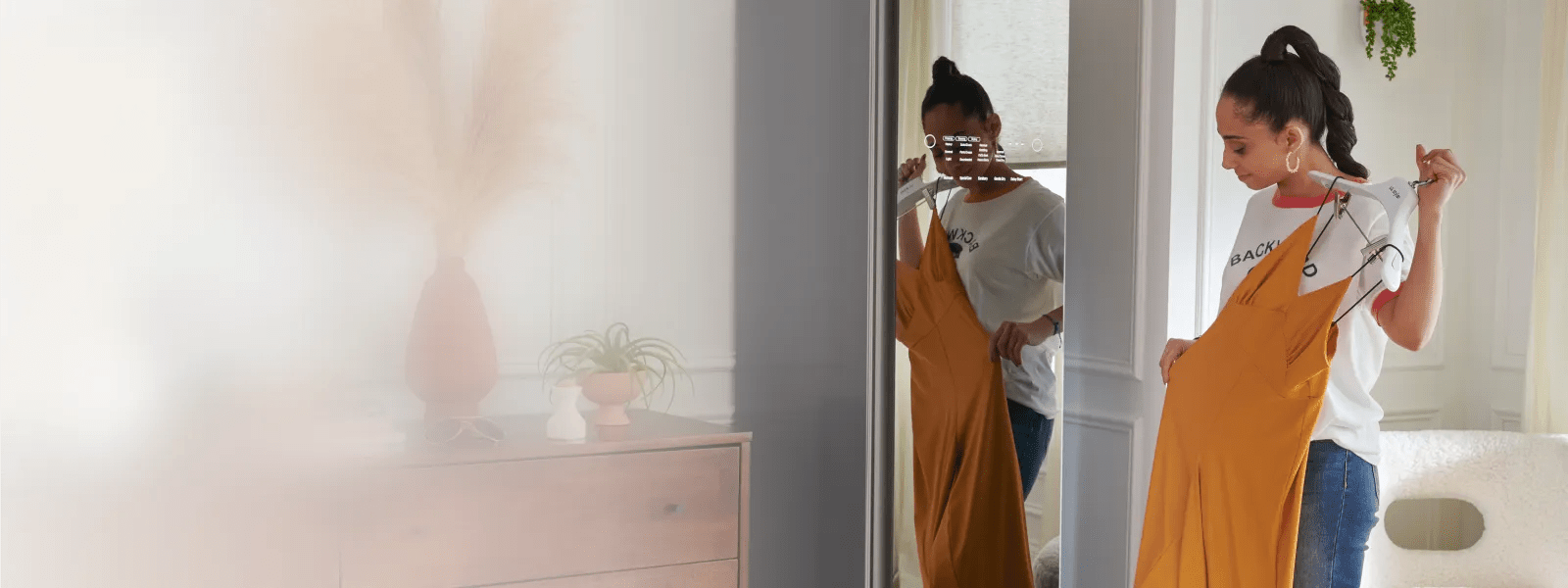 A woman holds a dress on a hanger in front of the LG Styler®'s mirrored door finish.