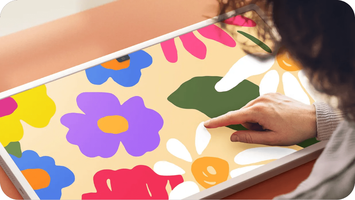 Person drawing a colorful floral illustration directly on LG StanbyME 2 touchscreen with their finger.