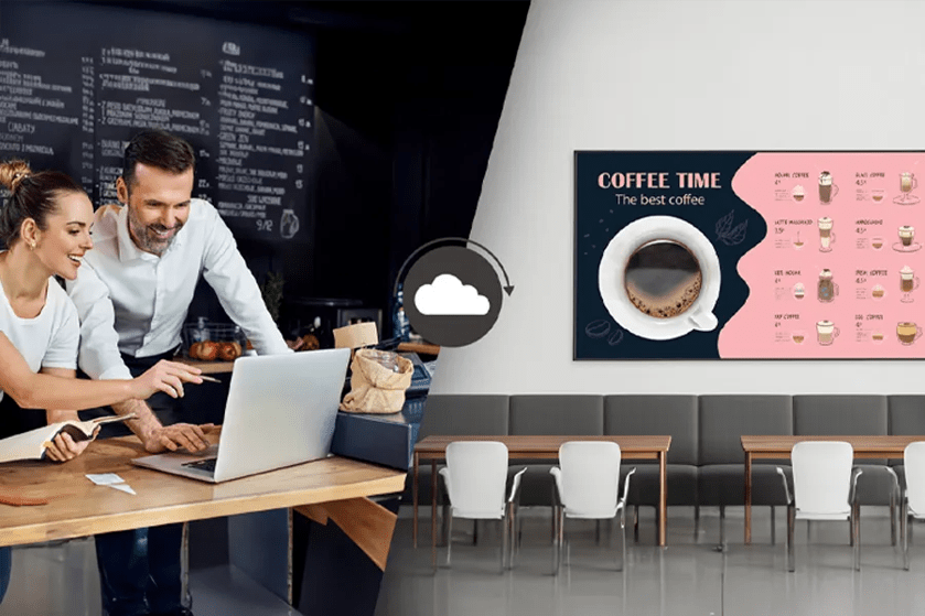 Café workers at a laptop; cloud icon; seating area with coffee menu poster.