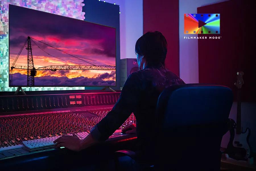 A man sits in front of a sound board watching a film on the LG UT7570 with FILMMAKER MODE™ logo.