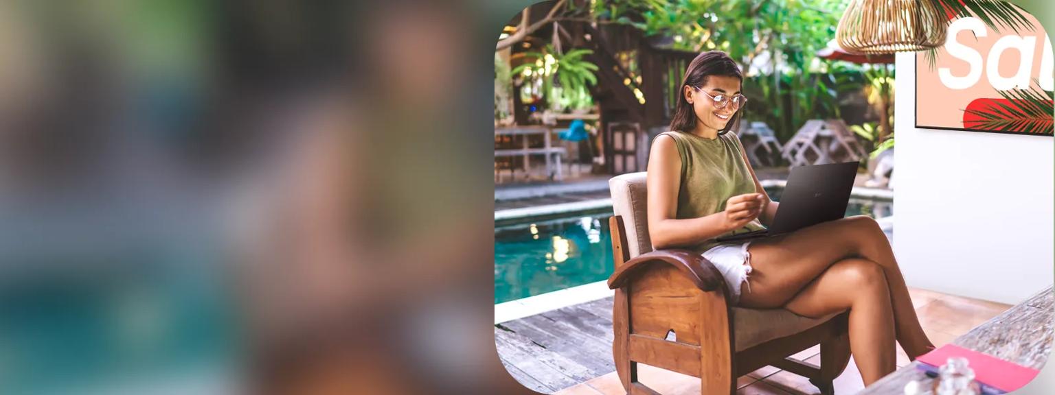 A woman uses an LG gram to work at a tropical resort. LG signage behind her advertises the promotional sale.