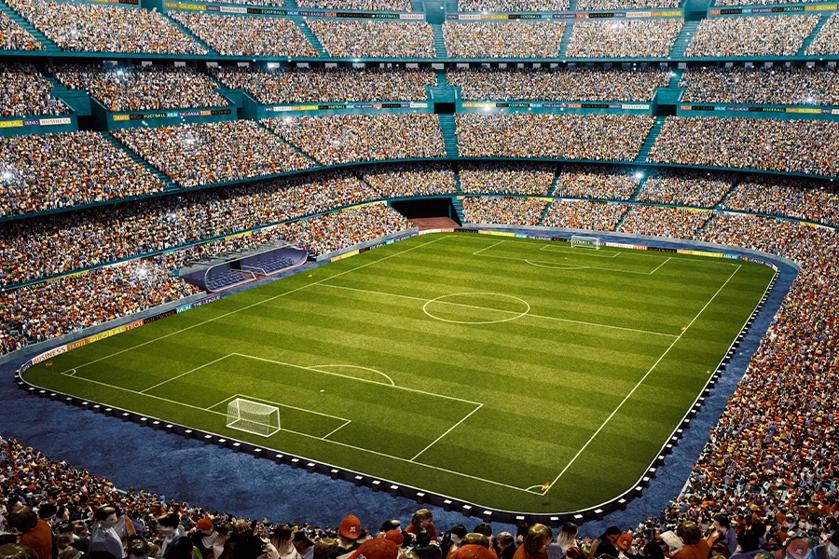 A packed soccer stadium with spectators and a green pitch.