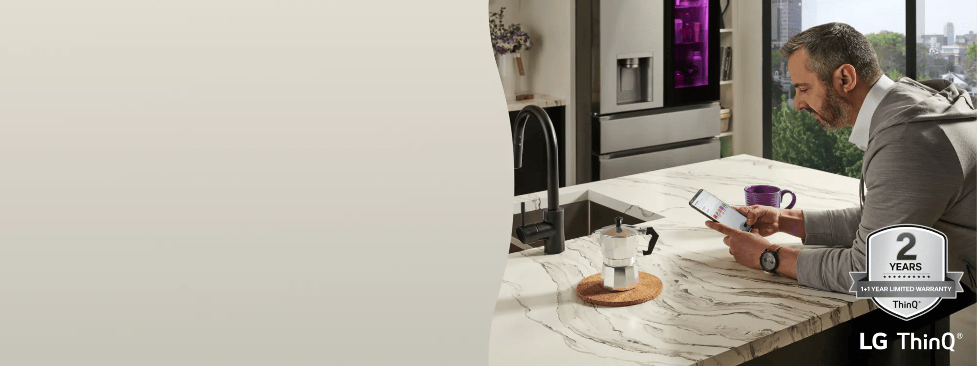 A man scrolls through ThinQ app in his kitchen. “2 Years ThinQ: 1+1 Year Limited Warranty” badge.