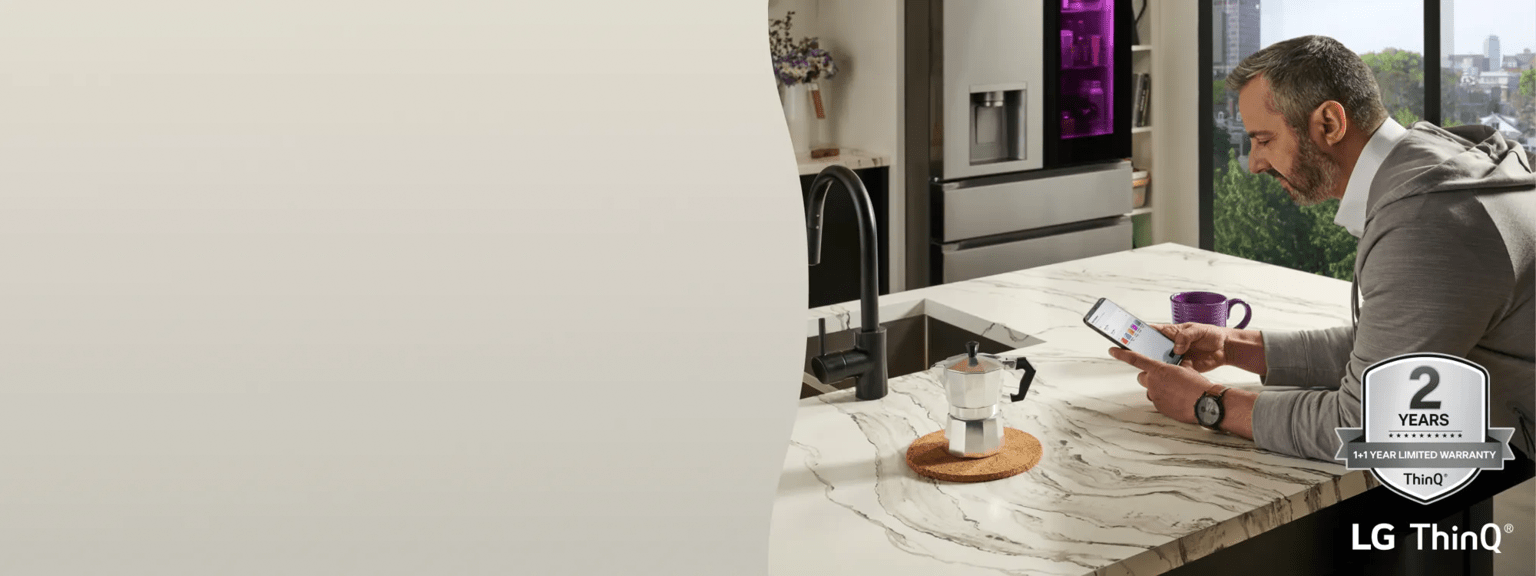 A man scrolls through ThinQ app in his kitchen. “2 Years ThinQ: 1+1 Year Limited Warranty” badge.