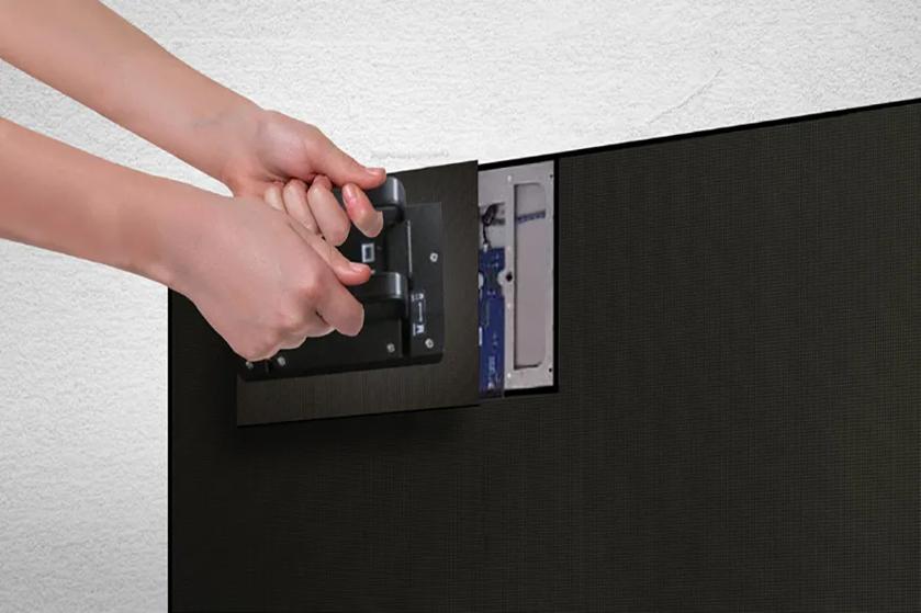 Hands removing an LED screen panel revealing internal components.