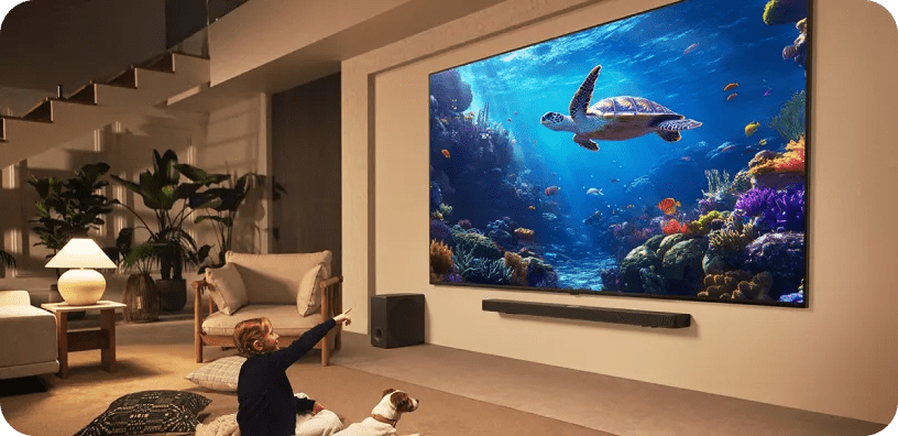 Woman with dog watching an underwater scene with a sea turtle on a wide-screen LG TV in a large living room.