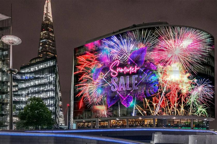 City night scene with a digital billboard displaying "Summer SALE" amid colorful fireworks and tropical leaves.