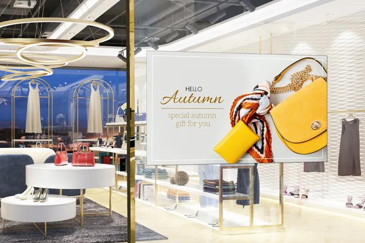 Modern retail store interior with an autumn-themed advertisement featuring a yellow handbag and scarf.