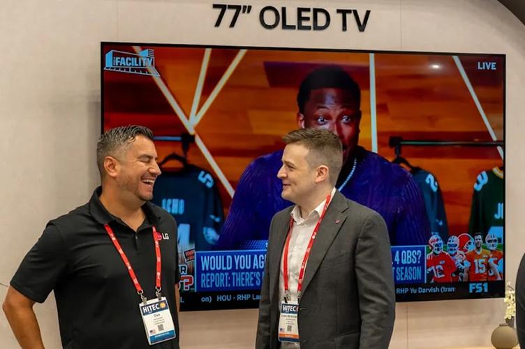 Two LG Sales employees laugh as they chat at a tradeshow.
