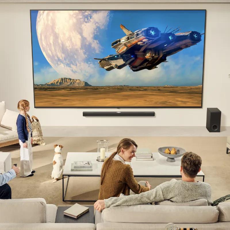 A family watching a movie on a wall-mounted TV in a living room.