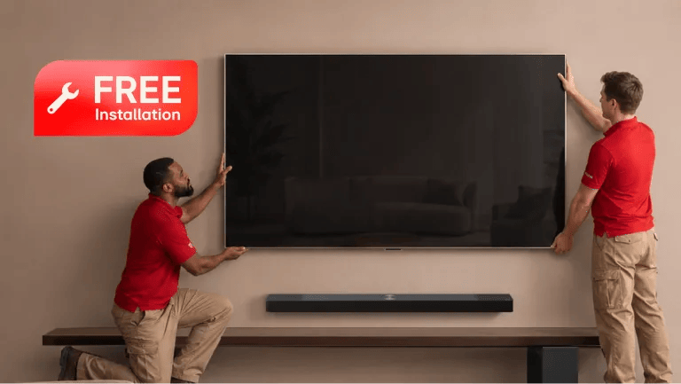 Two installers in red shirts mounting a large LG TV on a wall, with an LG Soundbar on a shelf below, and a "FREE Installation" badge with a wrench icon in the upper left.