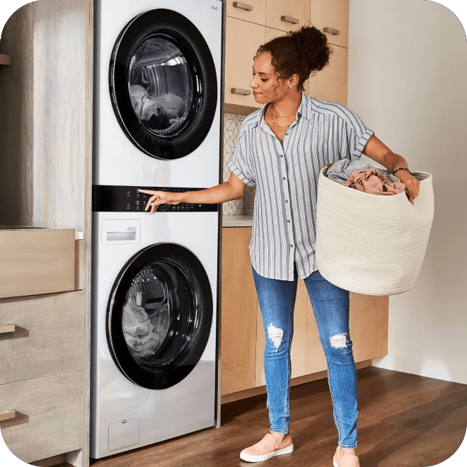 A woman is standing to the right of an all-in-one washer/dryer.
