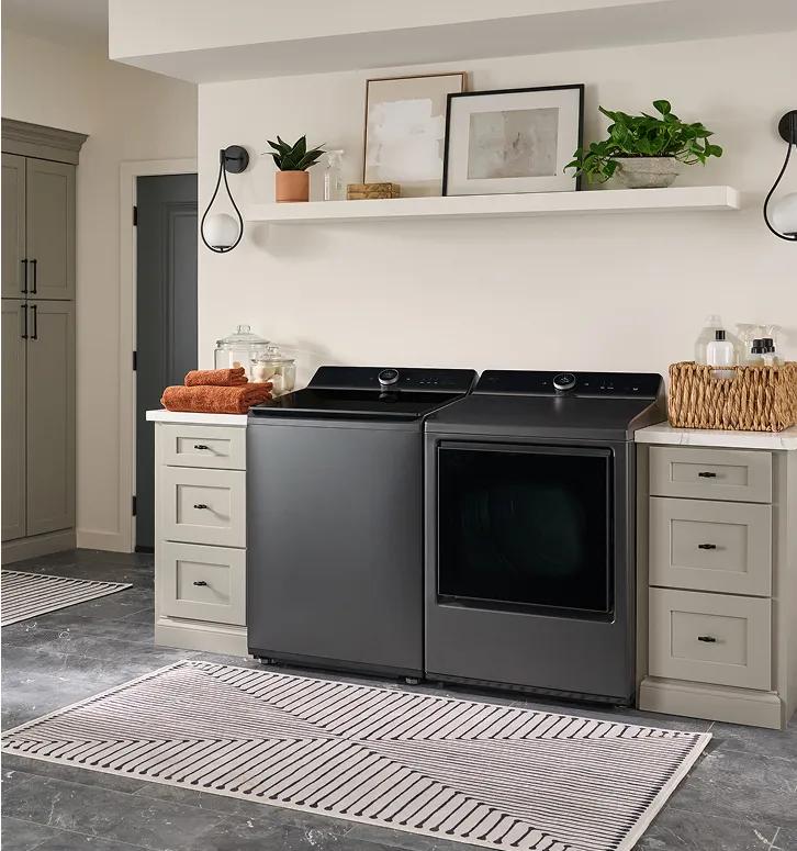 Dark gray top-load washer and front-dryer in a modern laundry room.