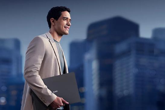 A businessman walks through a city holding an LG gram laptop